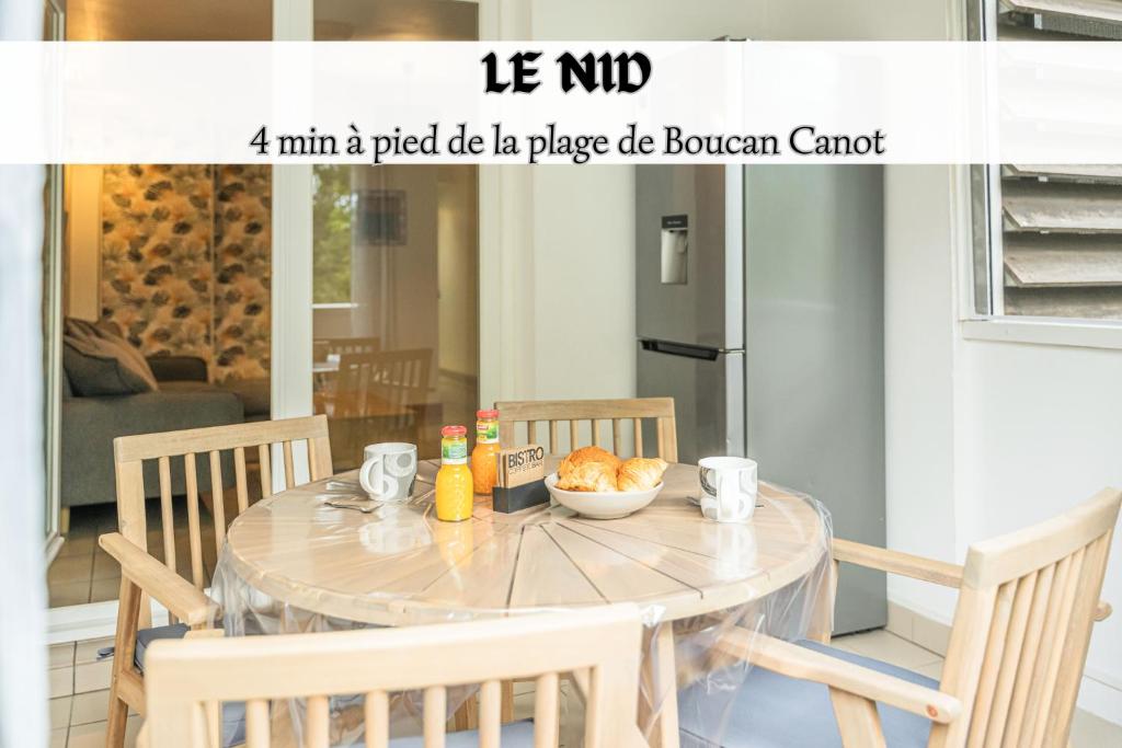 een eettafel met stoelen en een kom eten erop bij Le Nid - Cosy Plage & Confort - Wiskeys in Saint-Paul