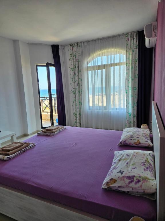 a bedroom with a large purple bed with a window at Lozenets Oasis Beach Home Lila in Lozenets