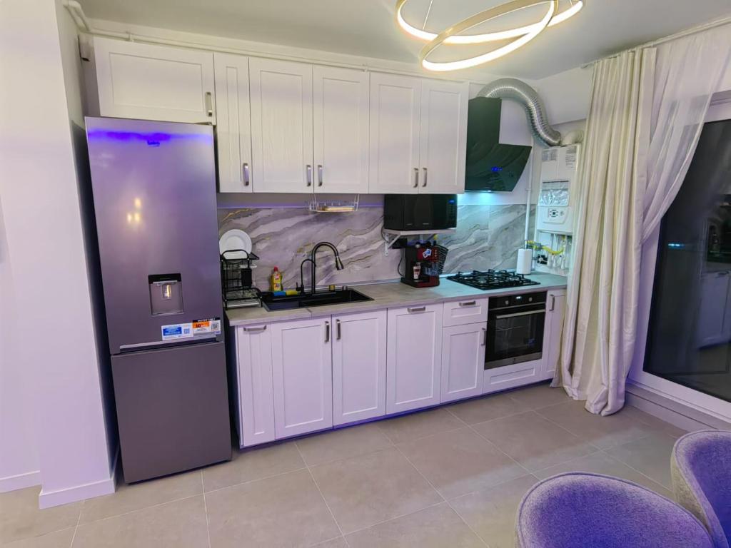 a kitchen with white cabinets and a purple refrigerator at Alezzi Odyssey in Mamaia Nord