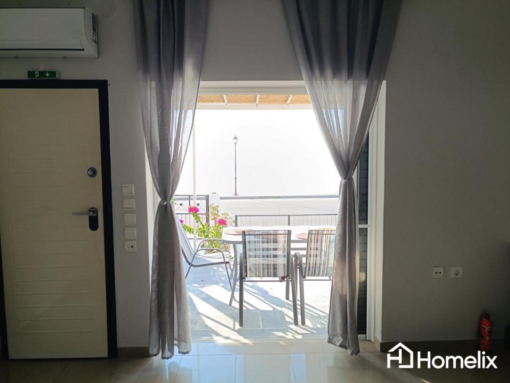 a door leading to a balcony with a table and chairs at C&K Beach Bungalow in Lefkandi Chalkidas