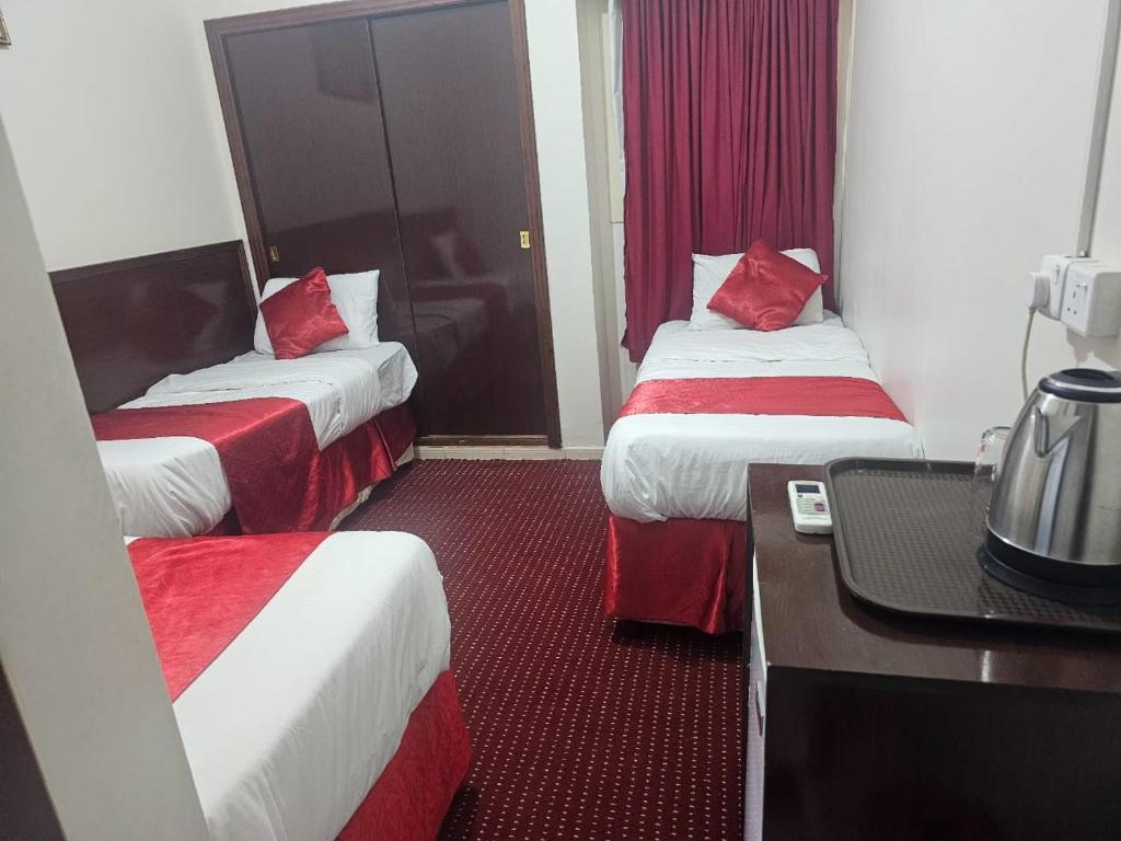 une chambre d'hôtel avec deux lits avec des draps rouges dans l'établissement فندق أركان الصفاء, à Ajyad