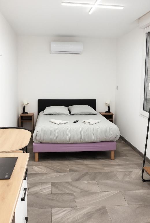 a bedroom with a bed and a desk with a laptop at Studio calme climatisé, Wi-Fi, arrivée autonome in Douai