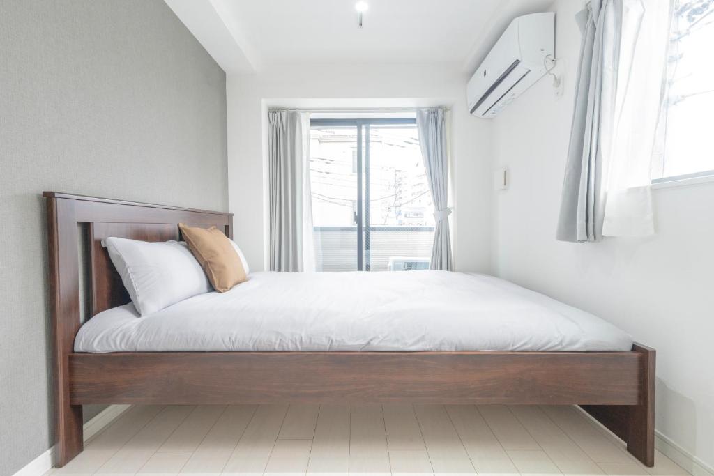 Un dormitorio con una cama con sábanas blancas y una ventana. en 三ノ輪駅徒歩圏 交通便利 浅草観光 ショッピング グルメを満喫する日本堤ステイ DsL, en Tokio