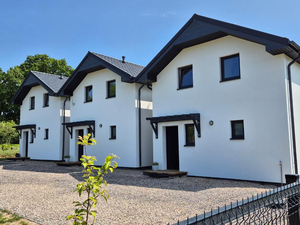 a row of white houses with black roofs at 9azaliowa - Domy całoroczne w Dębinie in Debina