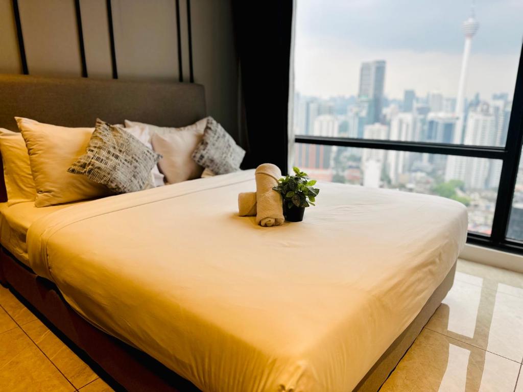 a bed with a teddy bear and a plant on it at Crystal Suites At Axon Residence in Kuala Lumpur