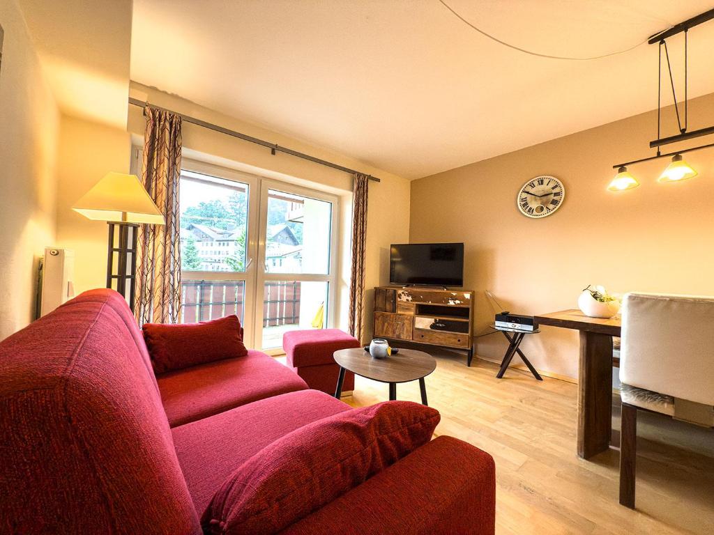 a living room with a red couch and a tv at Alm Loge in Oberstaufen
