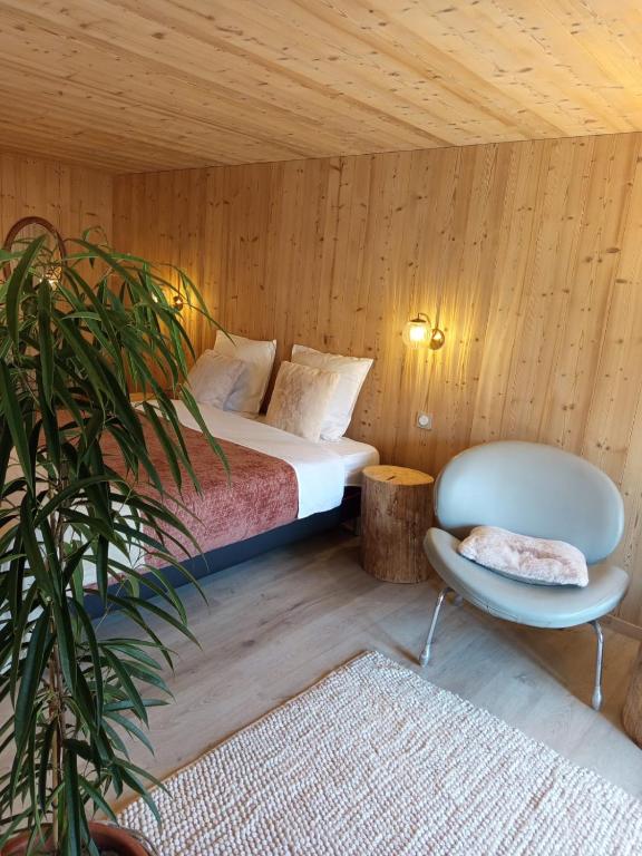 a bedroom with a bed and a chair and a plant at Au Mont Chablis in Champagnole