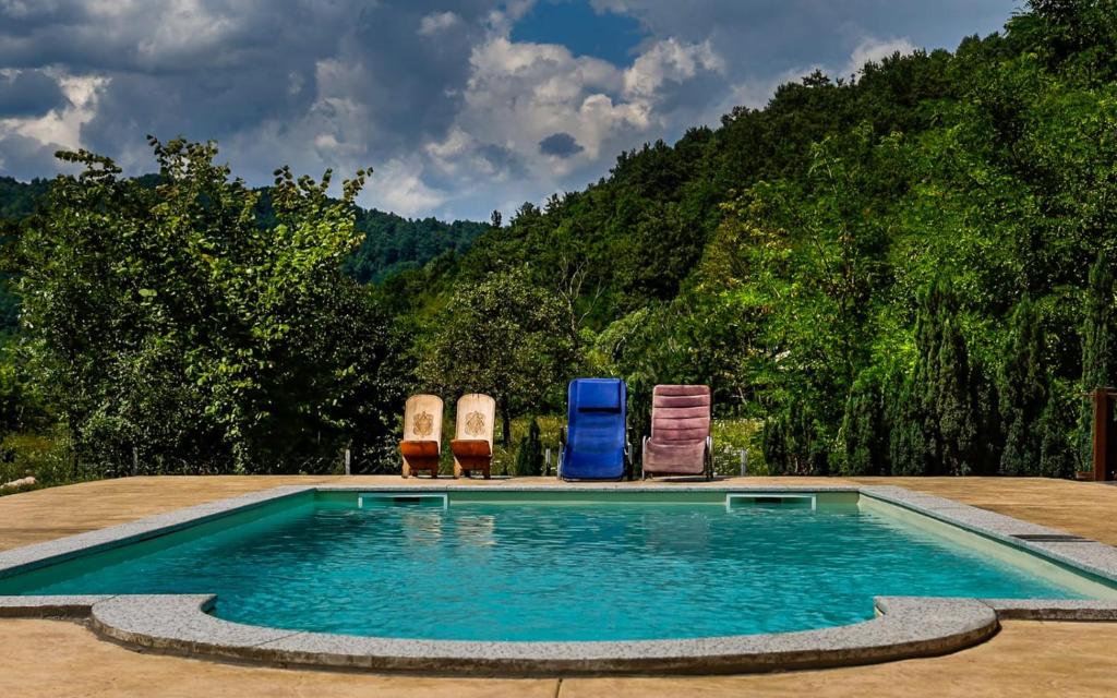a swimming pool with two lawn chairs and two chairs at Holiday house "Villa Dalia" in Bihać