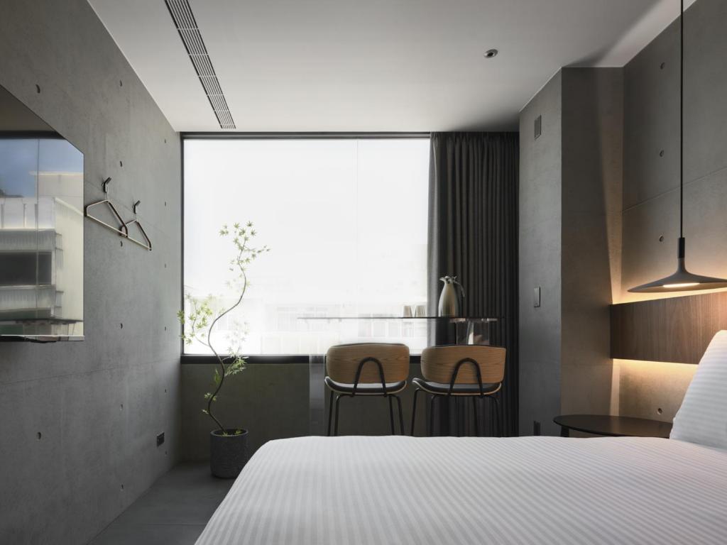 een slaapkamer met een bed, een tafel en stoelen bij Miu Hostel in Tainan