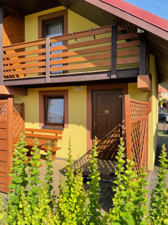 a house with a wooden deck and a porch at Domki w Rewalu - Promyczek Słońca in Rewal