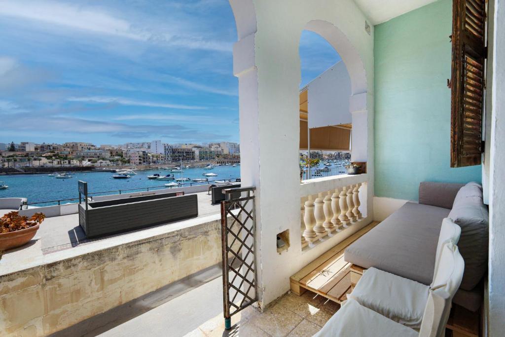 a balcony with a bed and a view of the water at Traditional Maltese Townhouse with Backyard Garden and Seafront Location in Taʼ Monita