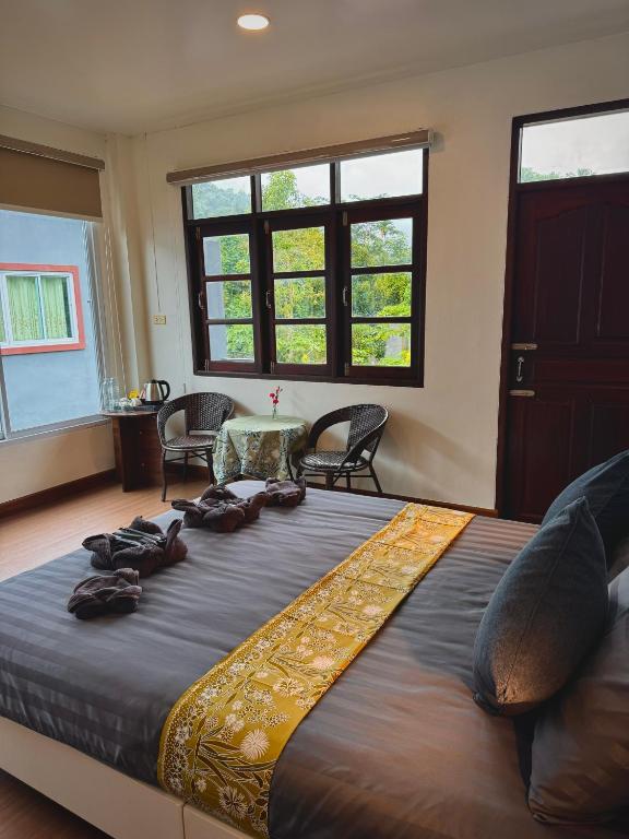 a large bed in a room with chairs and a table at khaosok Center Guesthouse in Khao Sok National Park