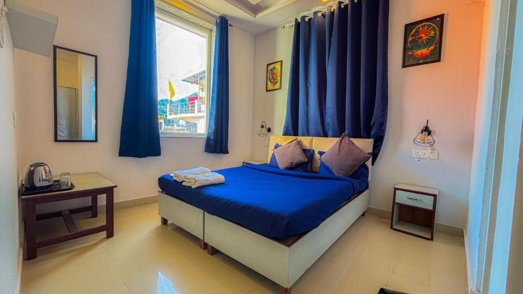 Un dormitorio con una cama con sábanas azules y una ventana. en Hop Inn Hostels Rishikesh, en Narendranagar