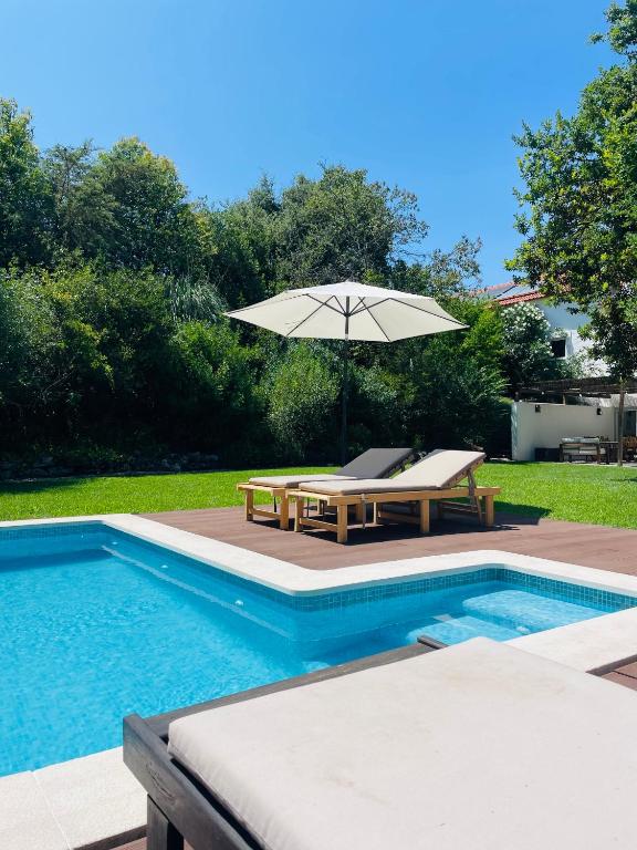 a swimming pool with an umbrella and a table and chairs at Casa das Ribeiras in Azoia de Baixo