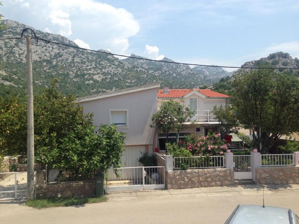 una casa con una valla y una montaña en el fondo en Apartments Tea, en Karlobag