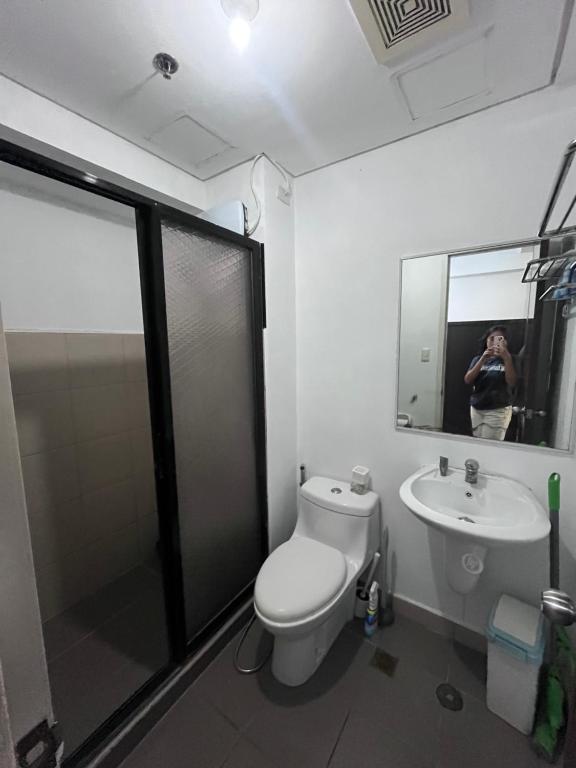 a person taking a picture of a bathroom with a toilet and sink at Avida tower 2 in Davao City