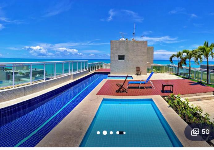 a swimming pool on top of a building next to the ocean at Apartamento JTR Maceio AL in Maceió