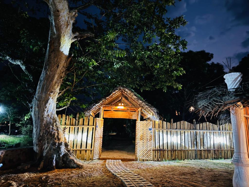 ein Holztor mit einem Zaun und einem Baum in der Unterkunft TravelLodge Eco in Arugam Bay