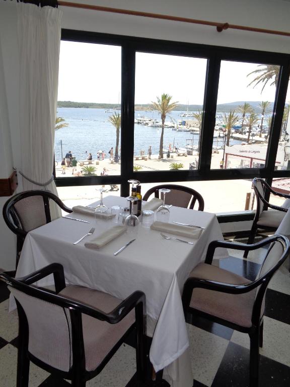 a dining room with a table and a view of the beach at Hostal S'Algaret in Fornells
