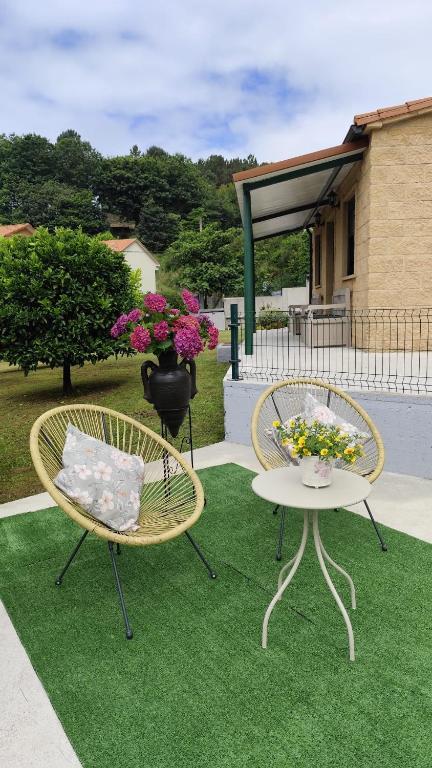 two chairs and a table with flowers on a lawn at A Devesa in Noya