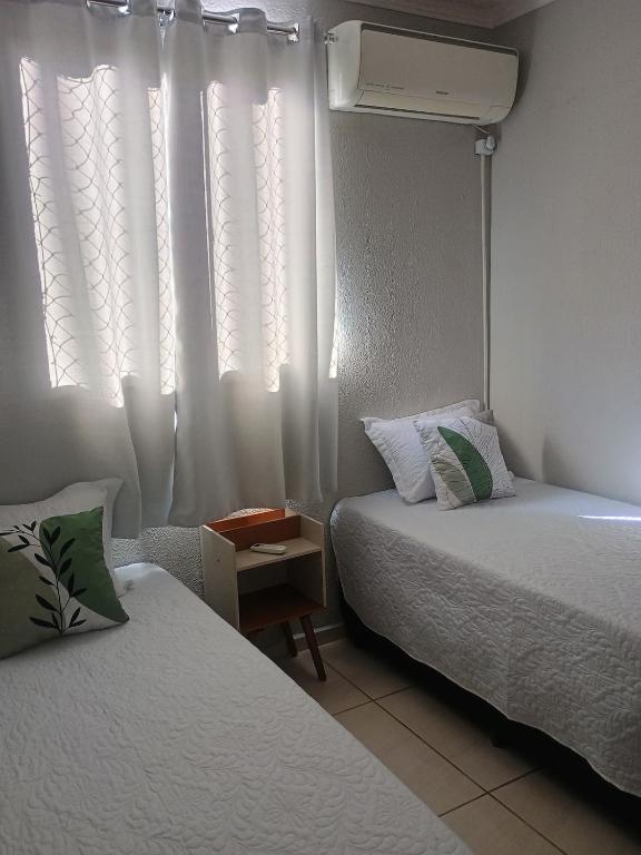 a bedroom with two beds and a window with curtains at La Bela Casa in Catanduva