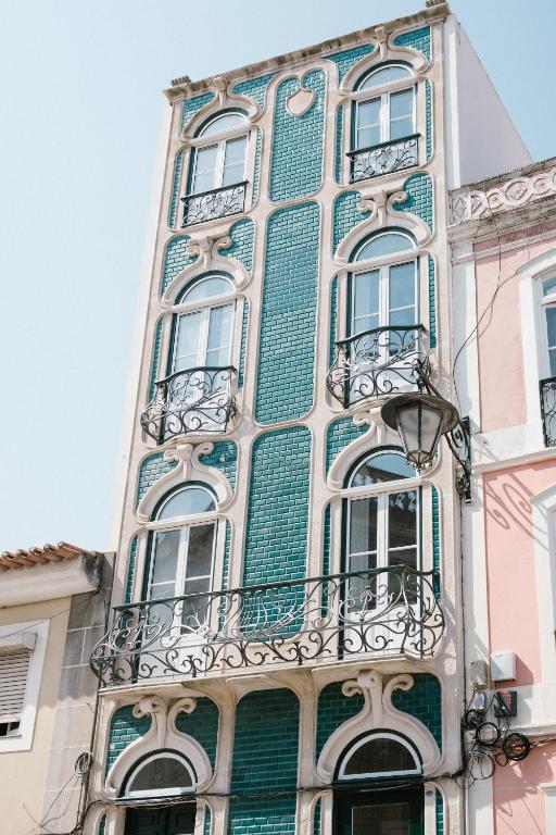 a tall green and white building with windows and balconies at Good Old Days - Guesthouse in Caldas da Rainha