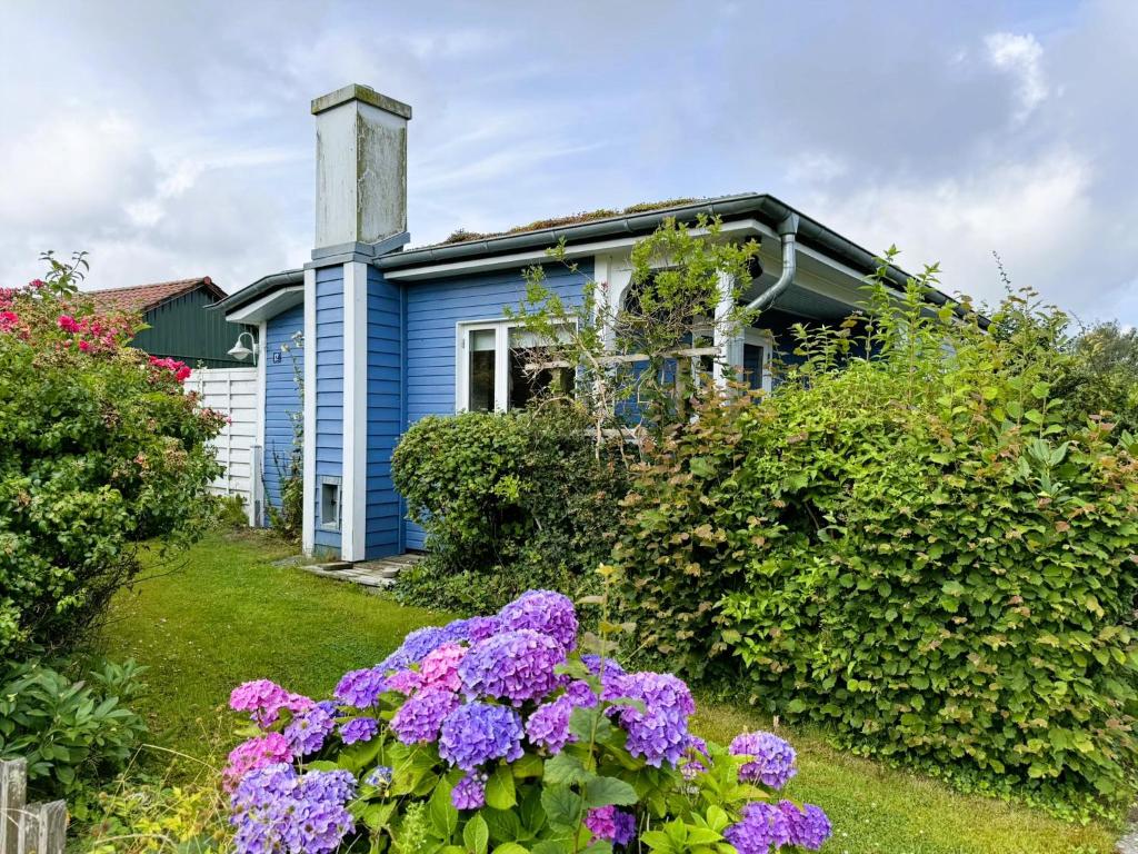 ein blaues Haus mit Blumen davor in der Unterkunft Blaue Pause - Hygge-Häuschen mit Garten und Kamin in Langballig