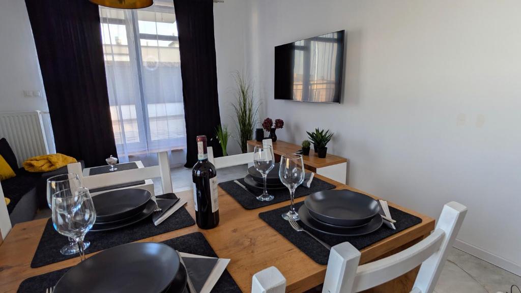 a dining room table with chairs and a table with wine glasses at Apartament Białołęka in Warsaw