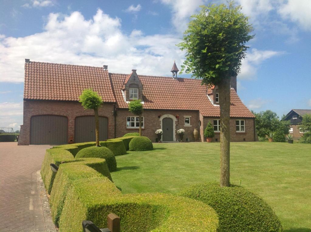 une maison avec un arbre dans la cour dans l'établissement B&B Decoster, à Zuienkerke