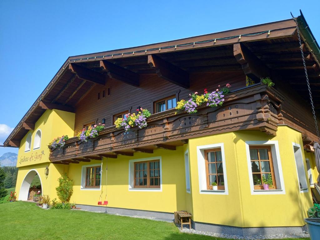 a yellow house with a balcony with flowers on it at Landhaus St. Georg in Sankt Martin am Tennengebirge