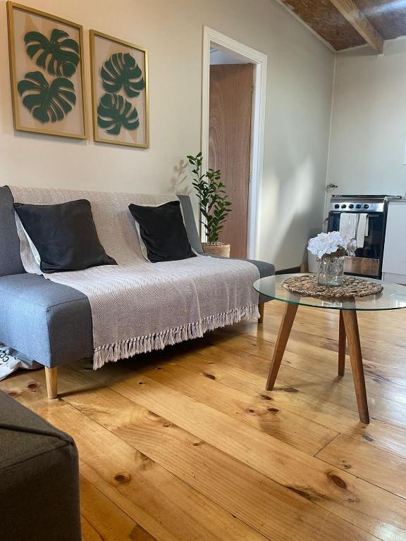 a living room with a bed and a glass table at Cabaña céntrica con vista al lago in Puerto Varas