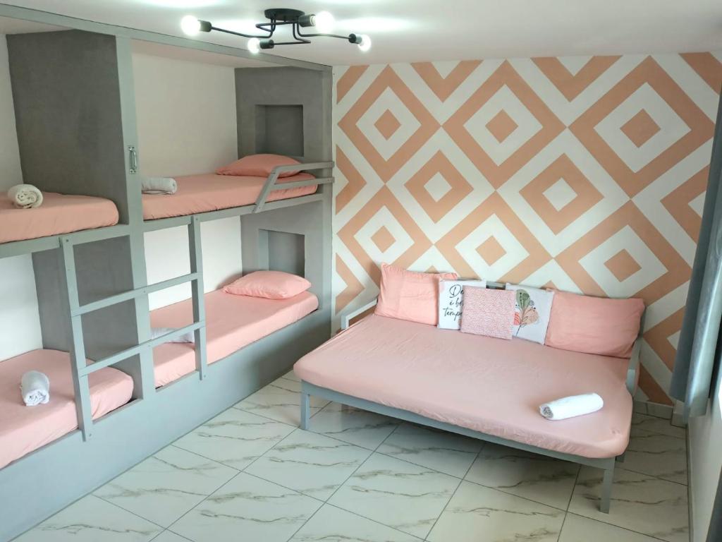 een kamer met roze stapelbedden en een bank bij Guará Apart 2 in Guaratuba