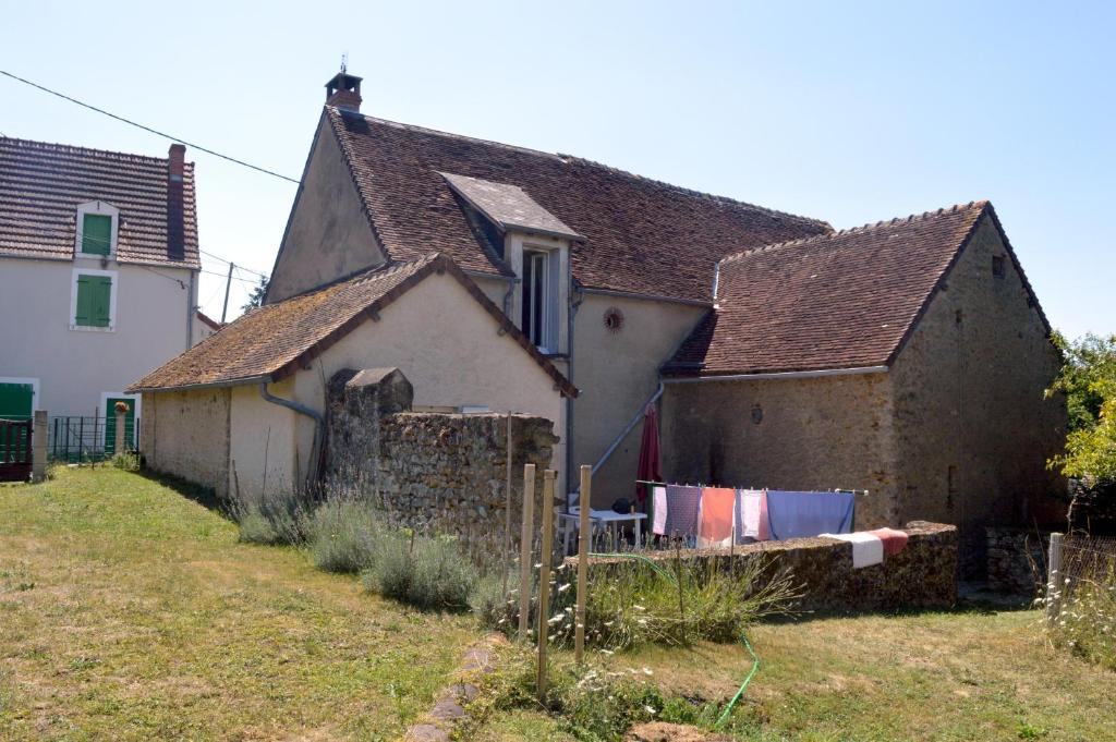ein altes Haus mit einer Wäscheleine davor in der Unterkunft Le Gîte du Hérisson, Gîte de charme et de confort in Le Menoux