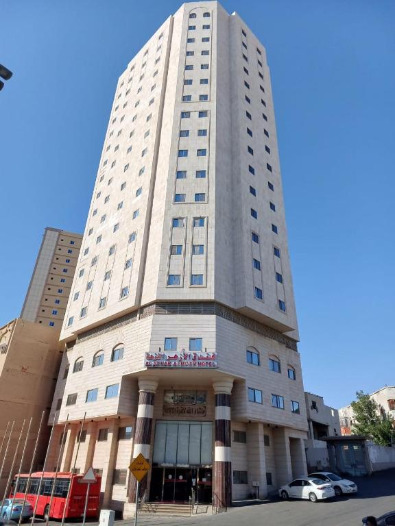 a tall white building with a red bus in front of it at فندق الأزهر النزهة - Al Azhar Nuzhah Hotel in Mecca