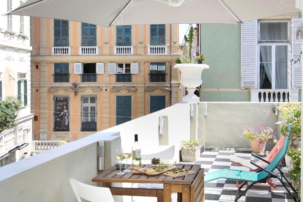 een balkon met een tafel en stoelen en een parasol bij La Genova storica dal monolocale in Genua