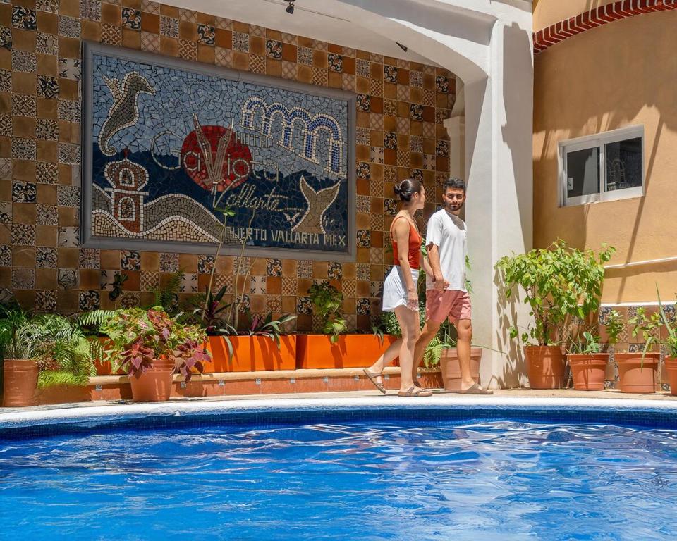 a man and a woman walking next to a swimming pool at Departamento Cielo in Puerto Vallarta