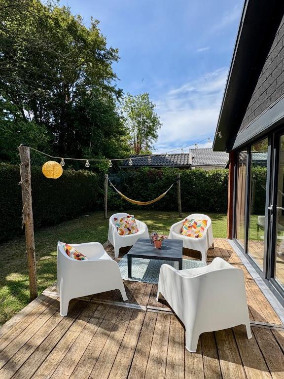 three white chairs and a table on a wooden deck at Oosterschelde Lodge met veel privacy en dicht bij het water in Scherpenisse