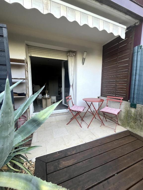 a patio with two pink chairs and a table at Studio pratique - Jardin privé in Grabels