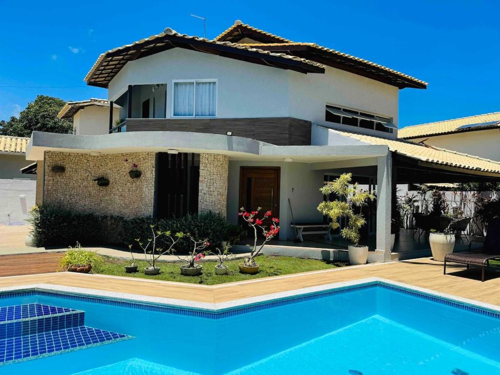 una casa con piscina di fronte a una casa di Casa 5 suites a 3 minuntos andando para o mar a Guarajuba