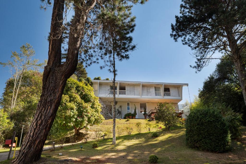 a large white house on a hill with trees at Casa Sabor Chocolate in Campos do Jordão