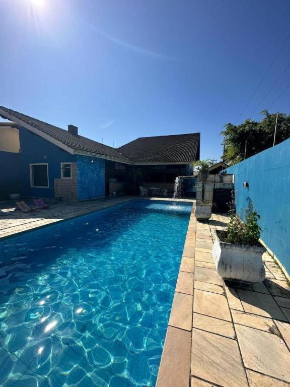 a swimming pool with blue water in a yard at Pousada Pérolas de Peruíbe in Peruíbe