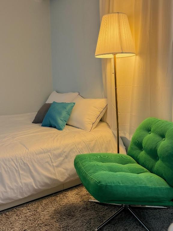 een slaapkamer met een bed met een lamp en een groene stoel bij Ahyeon Station 10-minute walk Cozy Stay in Seoul