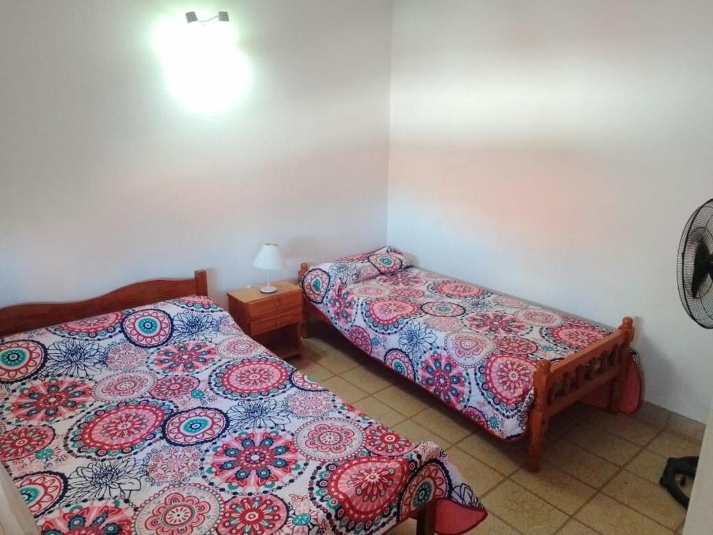 a bedroom with two beds and a table with a bedspread at Departamento para 5 personas en Mar De Ajó in Mar de Ajó