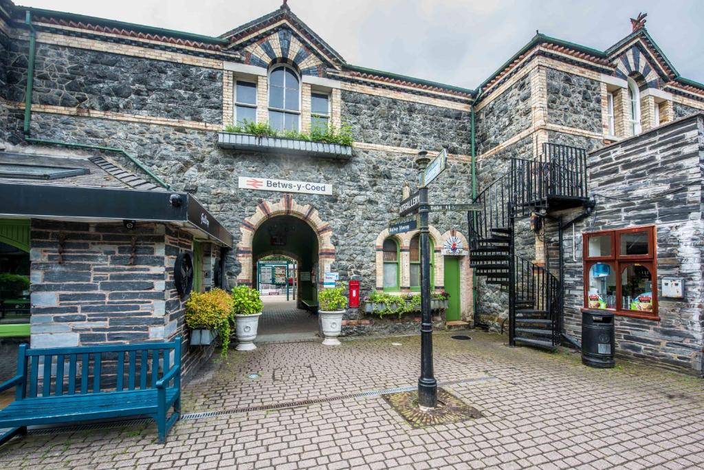a brick building with a blue bench in front of it at Alpine Apartments Snowdonia in Betws-y-coed