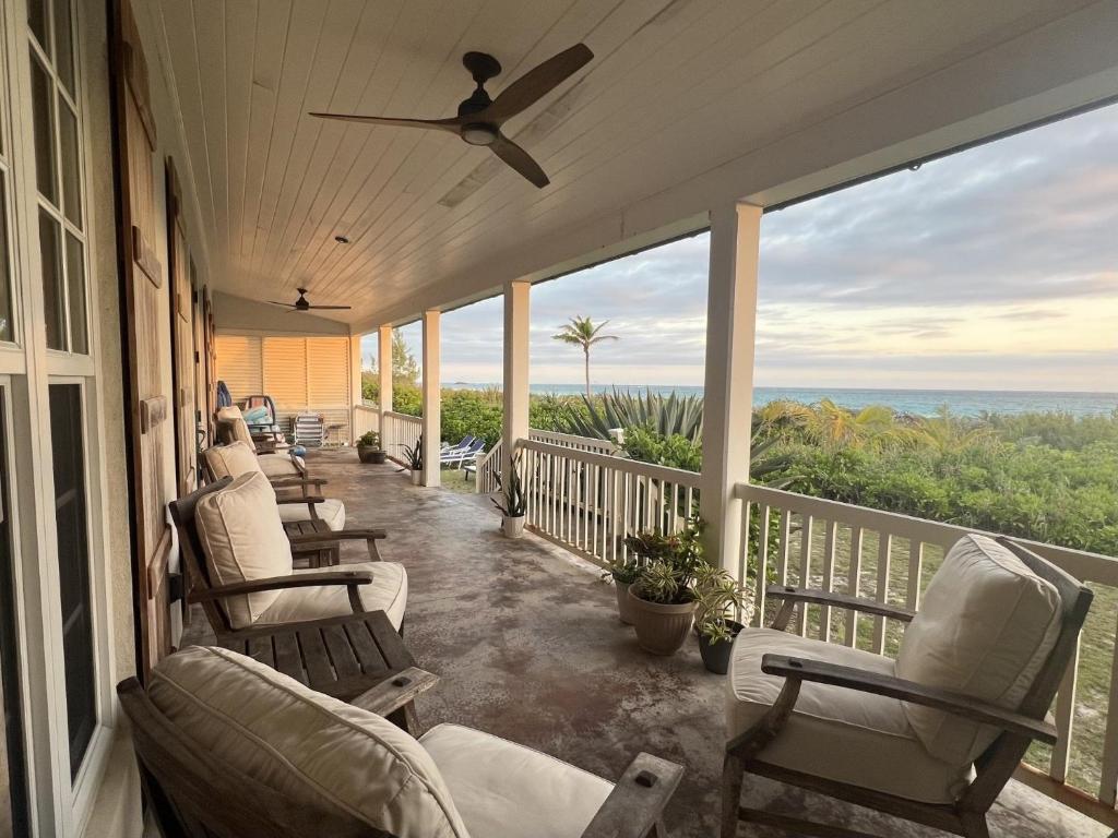 a porch with rocking chairs and a view of the ocean at French Leave South Beach Dogtrot Villa villa in Governorʼs Harbour