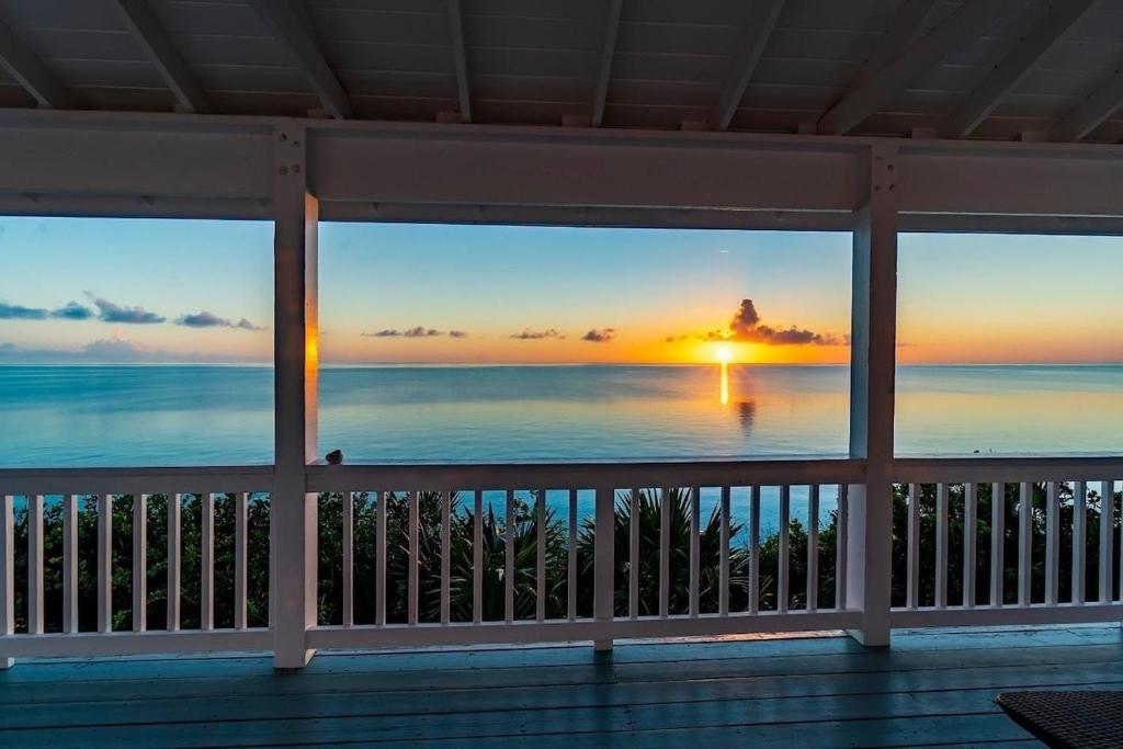 Blick auf das Meer von einer Veranda bei Sonnenuntergang in der Unterkunft Palm Bluff cottage in Gregory Town
