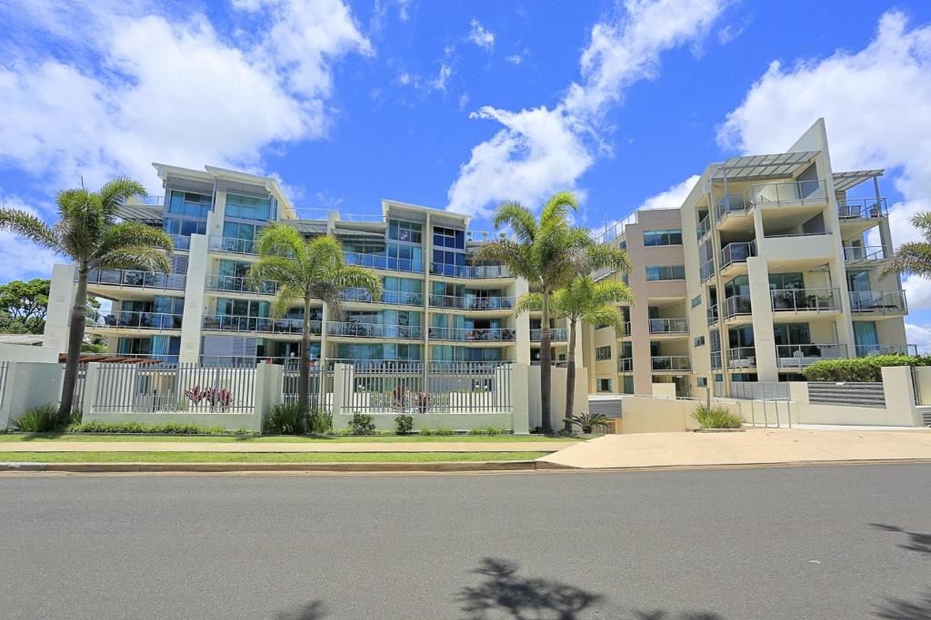 a large building with palm trees in front of it at Unit 37 Dwell in Bargara