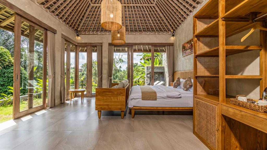 a bedroom with a bed in a room with windows at Tulip Villa Ubud in Ubud
