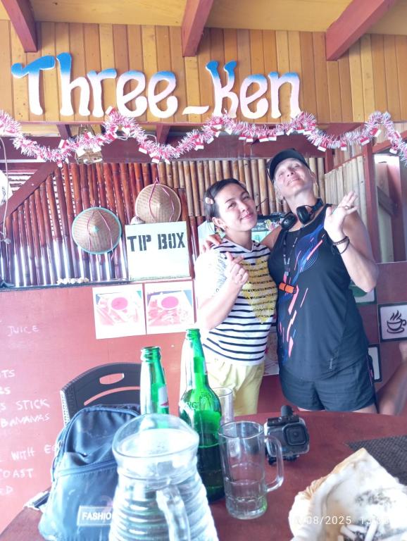 a man and a woman standing at a table at Three Ken Homestay & Cafe in Manado