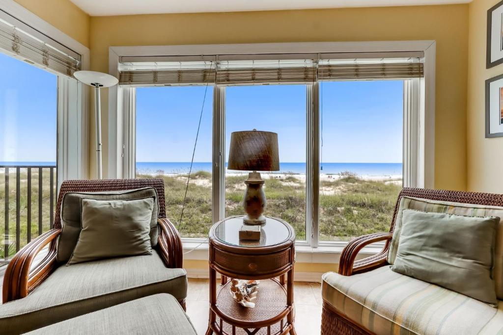 a living room with two chairs and a table with a lamp at Oceans Of Amelia - 104 in Fernandina Beach